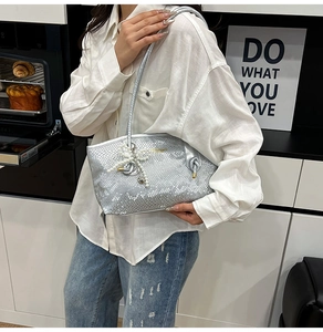 Detail of silver snake pattern shoulder bag with pearl heart charm in lifestyle setting