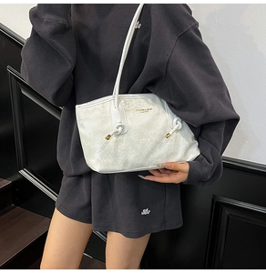 Close-up of white snake pattern leather bag with gold hardware and knotted strap details