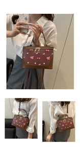 Detail view of vintage brown leather box bag featuring pink cherry print and gold zippers