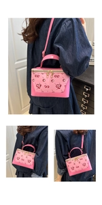 Detail of pink cherry print crossbody box bag with gold double zippers and handles