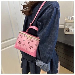 Pink cherry print crossbody bag showing side view and size on a person's shoulder