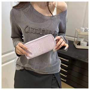 Detail of lavender snake-embossed long zipper wallet held by a model in a home setting