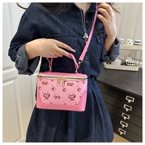 Detail of pink crossbody bag with cherry prints and dual metal zipper closure