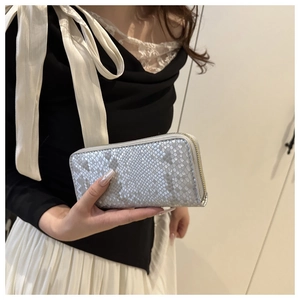Detailed view of silver long wallet featuring snake pattern and gold zipper detail
