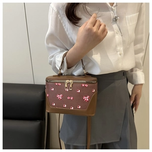 Detailed view of brown square crossbody bag featuring sweet cherry prints and top handle