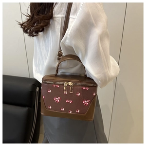 Macro view of retro cherry print handbag featuring gold zippers and premium leather texture