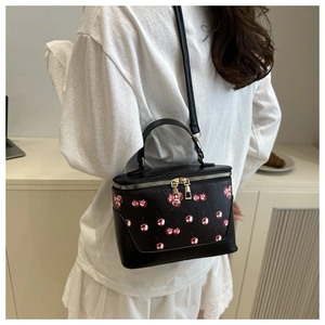 Detail of vintage bucket bag with cherry print and adjustable shoulder strap worn by model