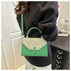 Detail of green woven crossbody bag with gold buckle and stylish top handle on a model