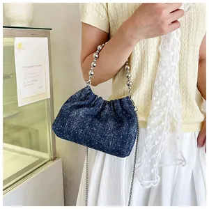 Detail der blauen Denim-Beuteltasche mit silbernem Perlengriff und funkelnden Strasssteinen