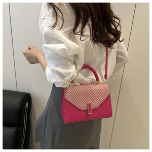 Side view of a bright rose pink crossbody bag with red and white chevron weave pattern