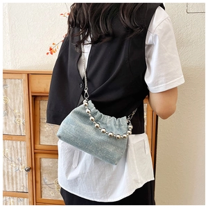 Detail der hellblauen Jeans-Beuteltasche mit Glitzersteinen und silbernem Perlengriff
