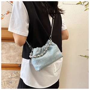 Detail der hellblauen Denim-Beuteltasche mit Silberperlen und Kettenriemen am Modell