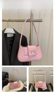 Detailed close-up of a pink crescent shoulder bag featuring a golden metal bow buckle