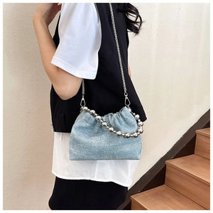 Detail der hellblauen Denim-Beuteltasche mit Silberkette und Perlen-Tragegriff