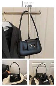 Detail view of black crescent moon bag with golden metal bow magnetic buckle