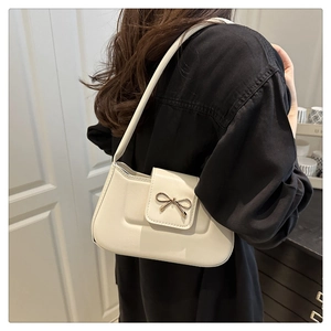 Détail du sac baguette blanc cassé avec une boucle décorative en forme de nœud doré