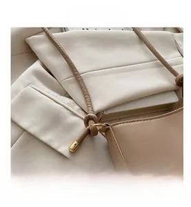 Detail of beige leather strap connector with golden ring hardware and round cord design