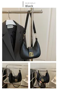 Detail of black leather crescent bag featuring a prominent gold geometric metal clasp