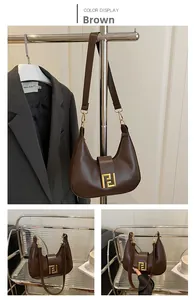 Detailed close-up of brown leather hobo bag with iconic gold geometric metal buckle