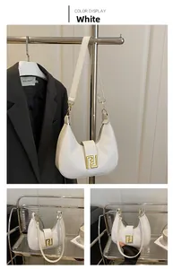 Detail view of white leather half-moon shoulder bag with golden F-shaped metal buckle
