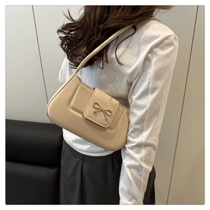 Detail of beige crescent bag featuring a silver metal bow buckle on smooth leather