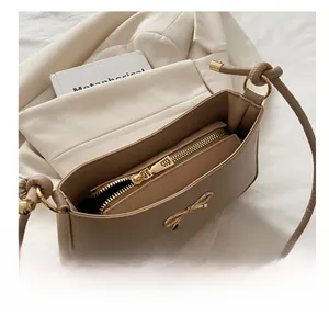 Close-up of beige PU leather shoulder bag interior with smooth zipper and metal bow detail