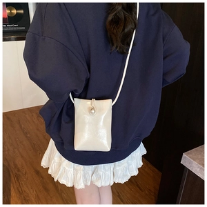 Chic cream mini crossbody phone bag with large pearl clasp shown on model for size reference