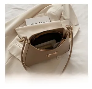 Interior view showing the large capacity of the beige bow shoulder bag on a blazer