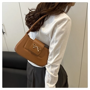 Détail du sac en similicuir caramel avec un fermoir nœud doré élégant et bandoulière fine