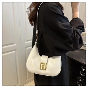 Detail of white half-moon underarm bag with gold logo buckle on leather surface