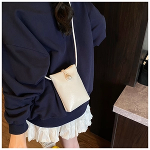 Detail of cream white leather mini crossbody bag with an elegant pearl buckle accent
