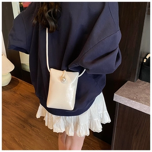 Detailed view of cream-white pearl buckle crossbody bag on model at waist side
