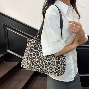 Grote canvas shopper met luipaardprint en zwarte leren riemen getoond op een model