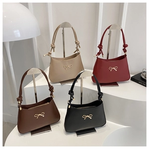 Detail showing elegant knotted shoulder straps and gold bow accents on leather bags