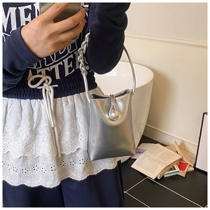 Detail of silver metallic mini bucket bag with thick chain handle and metal buckle