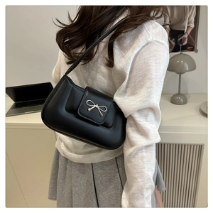 Gros plan d'un sac baguette en cuir noir avec une boucle nœud en métal doré