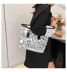 Detail shot of a large white tote bag with black street style graffiti on a female model