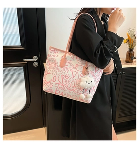 Close-up of doodle canvas tote with pink leather straps and a plush cloud charm detail