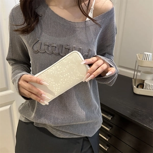 Minimalist sequined coin purse with compact zipper design held by a stylish person.