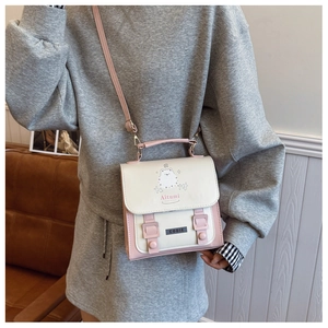 Détail du sac bandoulière rose et beige avec motif chat et boucles à double sangle