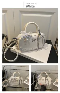 Detailed view of white PU leather bowling bag with lace trim and bow charm accessory