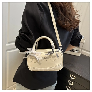Detail of cream bowling bag featuring delicate lace trim and colorful bow accents