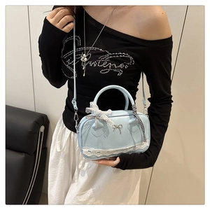 Close-up of light blue bowling bag with white lace trim and a metal bow pendant