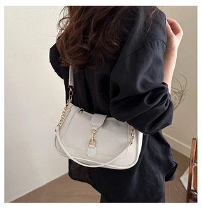 Détail du sac sous le bras en cuir crème avec boucle dorée et bandoulière en chaîne