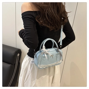 Detail of light blue lace Boston bag with metallic bow and checkered silk scarf handle