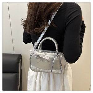 Silver mini Boston bag with white lace trim and bow detail shown on a shoulder
