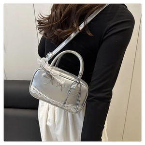 Detail of silver metallic bowling bag with white lace trim and a metal bow accent