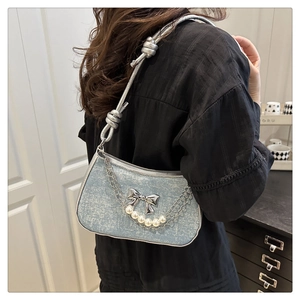 Detail of silver-blue denim texture bag with metallic bow and elegant pearl chain strap