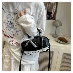 Detail of black bowling bag featuring white lace trim and bow knot with a metal buckle