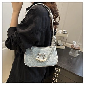 Detail of light blue textured shoulder bag with silver bow, pearls and metal chain strap
